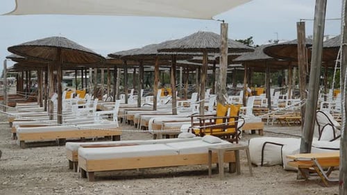 Sun Loungers with Umbrellas on an Empty Beach Without People in Cloudy Weather
