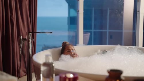 Woman Relaxes in Bubble Bath with Wine