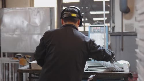 Worker Operating Machinery in a Metal Fabrication Workshop Wearing Protective Gear Focusing on the