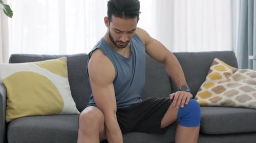 Man Lifting Dumbbell on Sofa at Home