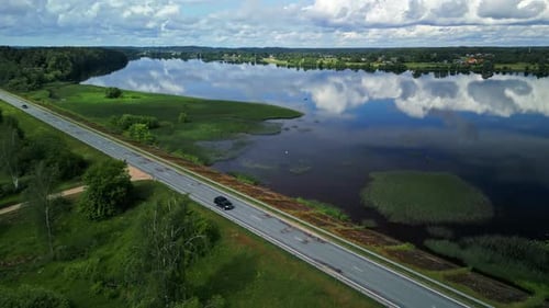 Stunning Aerial View of a Serene Lake and Scenic Roadway Surrounded By Natures Beauty and