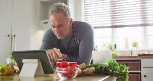 Man in Kitchen Using Tablet for Recipe