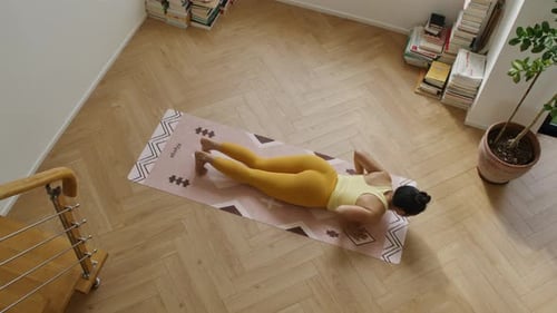 Vue de haut en bas d'une jeune femme asiatique en forme athlétique pratiquant le yoga san salutation dans sa chambre d'appartement
