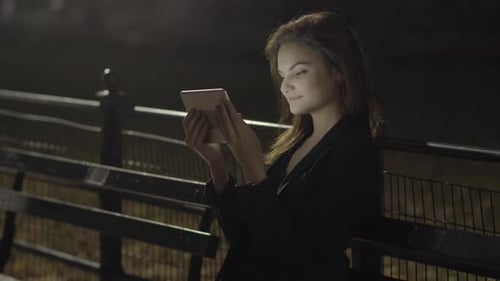 Young Woman Using Tablet Computer In The Park At Night