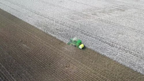 Imágenes aéreas de un recolector de algodón Baler de seis hileras trabajando en un campo.