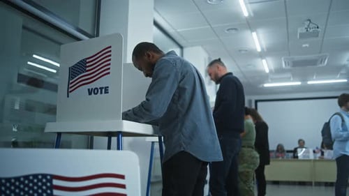 African American Man Votes in Booth in Modern Polling Station
