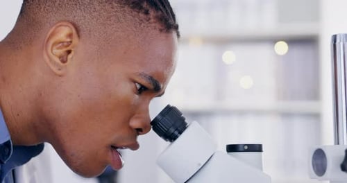 Young Adult Using Microscope in Modern Laboratory