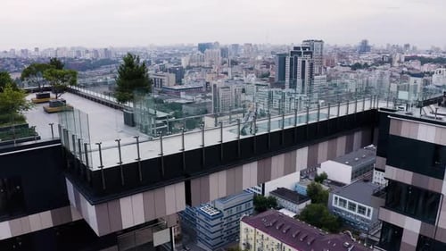 Beautiful young girl in a long dress walks across the bridge on a skyscraper. Aerial view