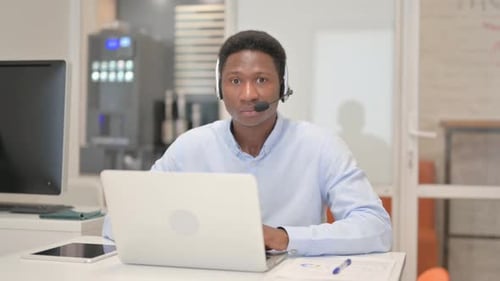 African Man with Headset Looking at Camera in Call Center