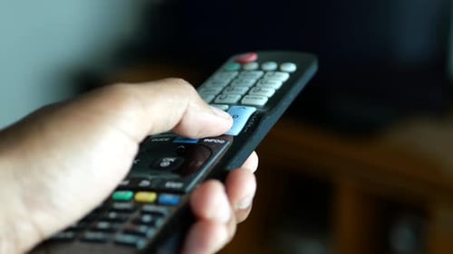 Nahaufnahme eines Mannes, der die TV-Fernbedienung hält
