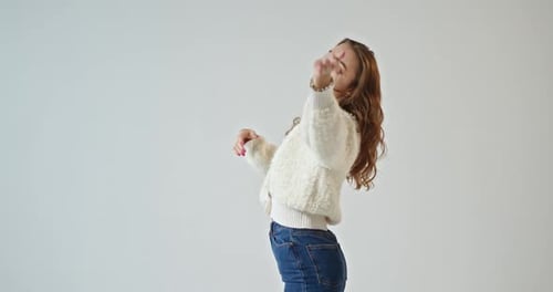 Cheerful Woman Dances in Jeans and Cardigan