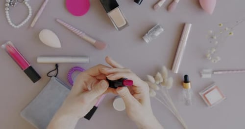 Blick von oben auf eine weibliche Hand, die Lippenstift hält und auf die Haut aufträgt und die Farbe mit diversem Make-up überprüft