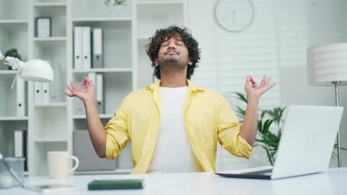 A calm employee worker practices yoga at the workplace in the office Happy freelancer programmer or