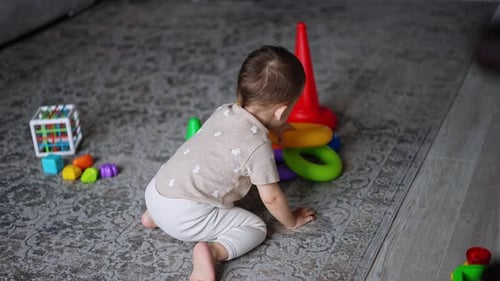 Baby Crawling on Rug Surrounded by Toys