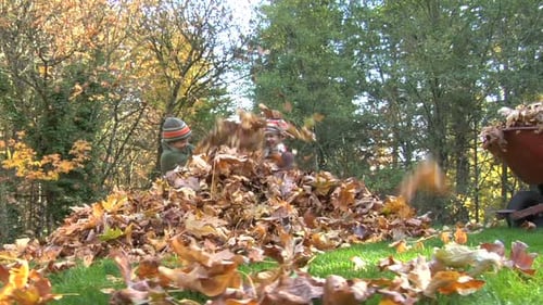 Los niños lanzan juguetonamente hojas de otoño en el patio trasero en un hermoso día de otoño
