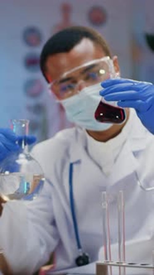 Scientist Holds Flasks with Liquids in Laboratory