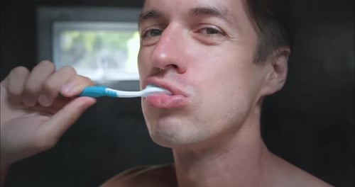 Young Adult Man Brushing Teeth in Bathroom Close Up