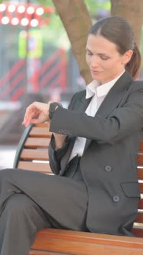 Woman in Business Suit Checking Smartwatch on Bench