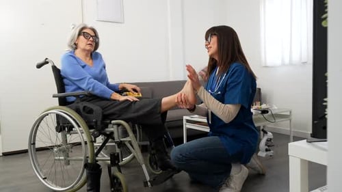 Woman in Wheelchair Receives Foot Massage from Healthcare Worker