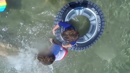 Bird's eye view of caucasian family swimming at sea with clear green waters, slow motion