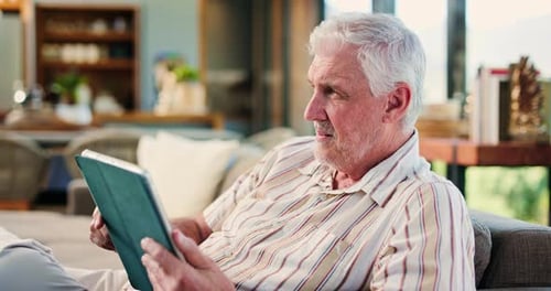 Senior Man Relaxing on Sofa with Tablet Indoors