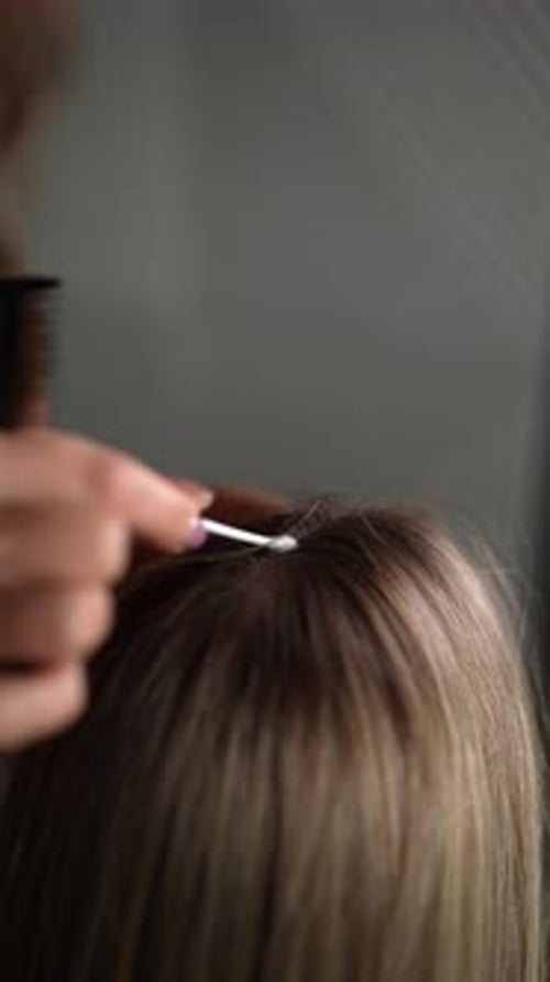 Woman Getting Hair Parted with Comb and Swab