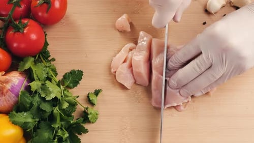 Mann schneidet rohes Truthahn- oder Hühnerfleischfilet auf Eichenschneidebrett in Scheiben, Nahaufnahme, Kochen mit Messer