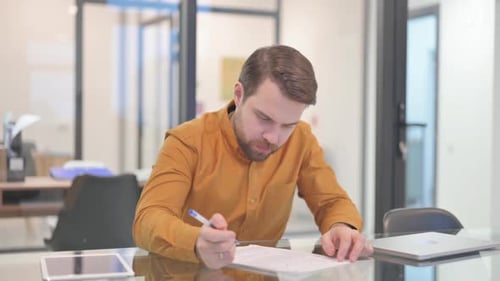 Man Reviews Documents at Office Desk