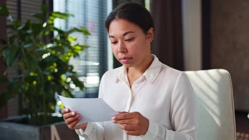 Mujer sentada en el espacio de trabajo y leyendo una notificación negativa con ojos grandes
