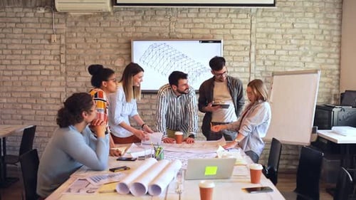 Group of young business people discussing architectural designs in office.