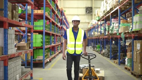 Warehouse workers pushing a pallet truck in a shipping and distribution warehouse.
