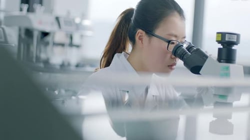 Young Woman Using Microscope in Bright Modern Lab
