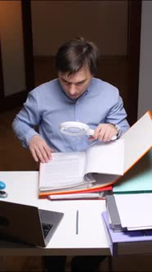 Vertical Video Office Worker Examining Documents with Magnifying Glass at Desk