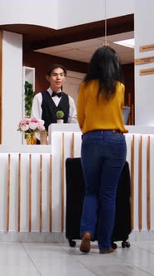Vertical Video Asian Guests Approach Reception to Ask About Accommodation