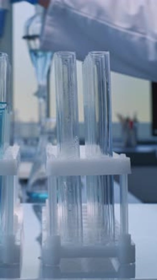 Gloved Hand Adding Liquid to Test Tubes