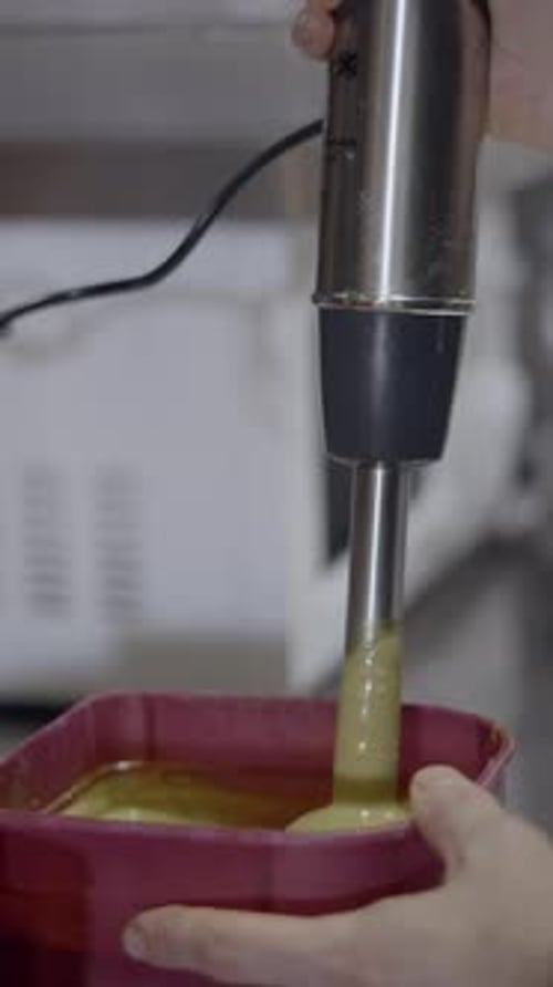 Close Side View of Immersion Blender Mixing Sauce in Plastic Container