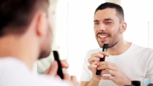 Man Combs Beard and Sings Into the Mirror