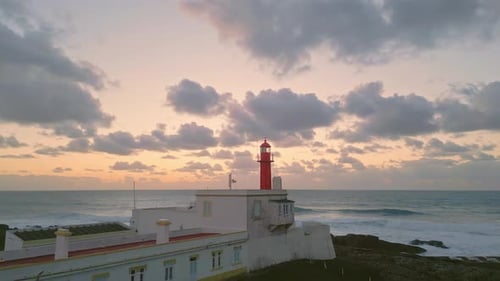 Vom Leuchtturm beleuchteter goldener Sonnenuntergang mit Drohnenblick Malerischer goldener Sonnenuntergang über dem Meer
