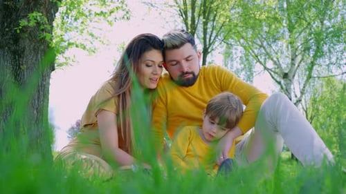 Loving Family Embracing in a Park on Green Grass