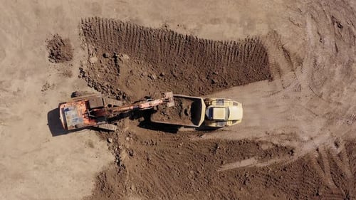 Excavator loading soil onto a Truck, Aerial view.