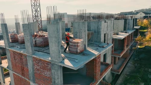 Vista aérea: Trabajador de la construcción en la obra Trabajador con chaleco de alta visibilidad caminando sobre concreto