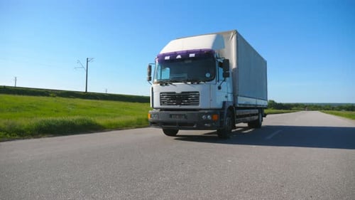 Camera Follows to Truck with Cargo Trailer Driving on Empty Highway Transporting Goods at Summer Day