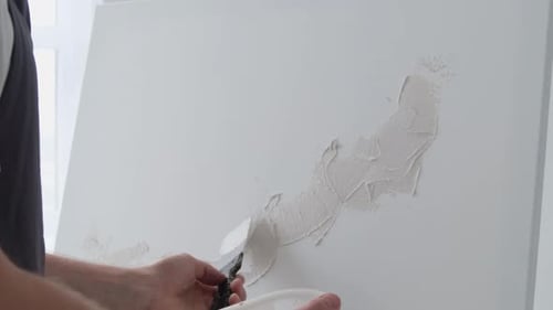 A Young Artiste Paints White Paint on a Clean White Canvas