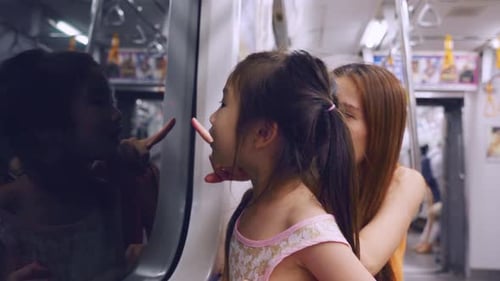 Una joven asiática mira a la vista mientras viaja en el tren con su madre.
