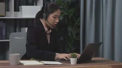 Professional Woman Using Laptop with Headset in Office