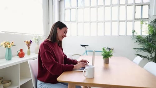 Young Woman Working on Laptop in Bright Home Office