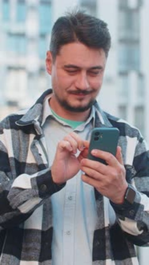 Smiling Mature Man Tourist Chatting on Internet Via Mobile Phone Standing on Downtown City Street
