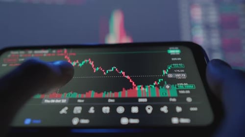 The Investor Carefully Studies the Charts and Charts of the Financial Market on His Smartphone