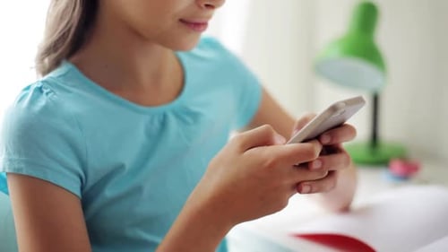 Teen Girl Using a Smartphone Indoors at Desk