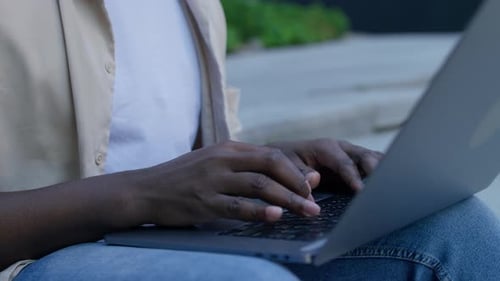 Nahaufnahme von Händen, die draußen auf einem Laptop tippen